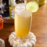 Glass of yellow cocktail with lime wheel on a wooden table