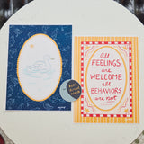 Two printed cards placed side by side on a round white table. The left card has a dark blue background with a white duck illustration inside a yellow oval border. The right card has the text "all feelings are welcome all behaviors are not" in red on a yellow and pink background.