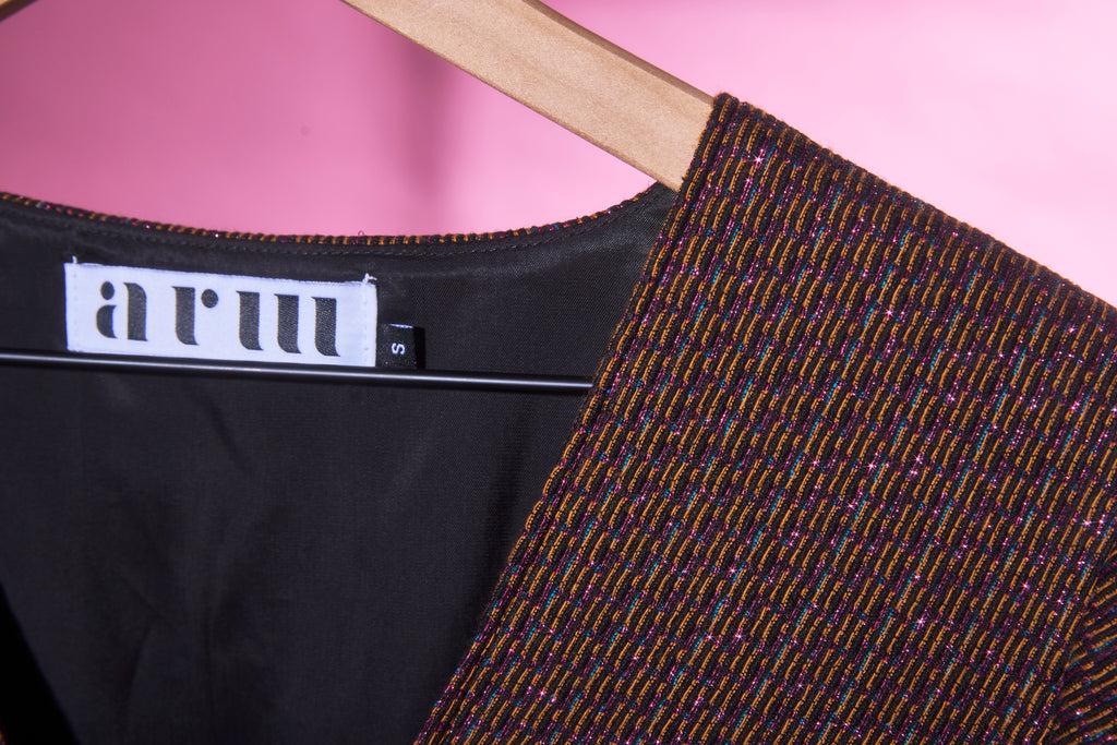 a closeup of the metallic jacquard fabric used in ARW's deep V block dress. Light is reflecting off the metallic thread.
