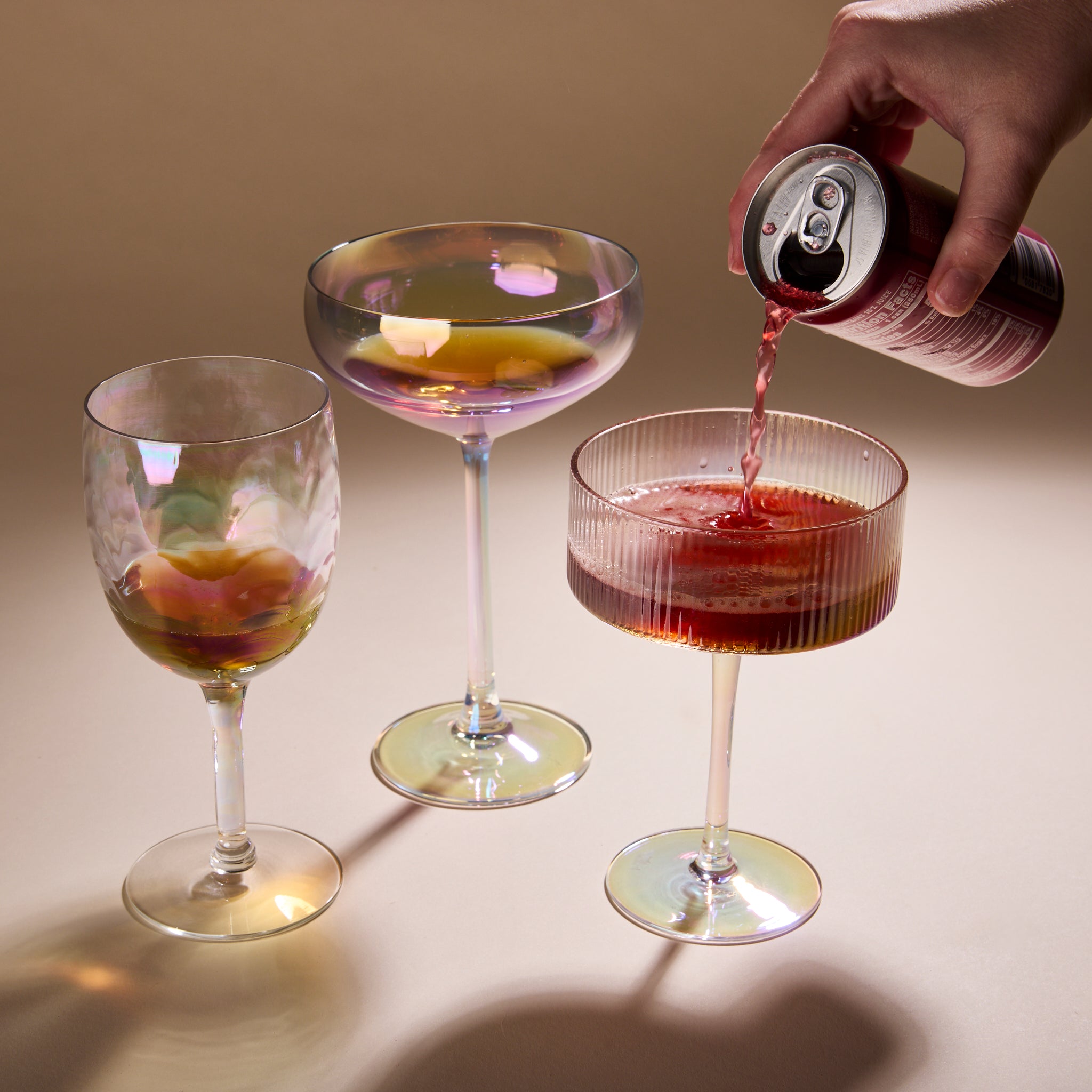 Cup of Communitea's tea infused simple syrups, each poured into cocktail glasses. A hand is pouring a beverage into one of the glasses. 