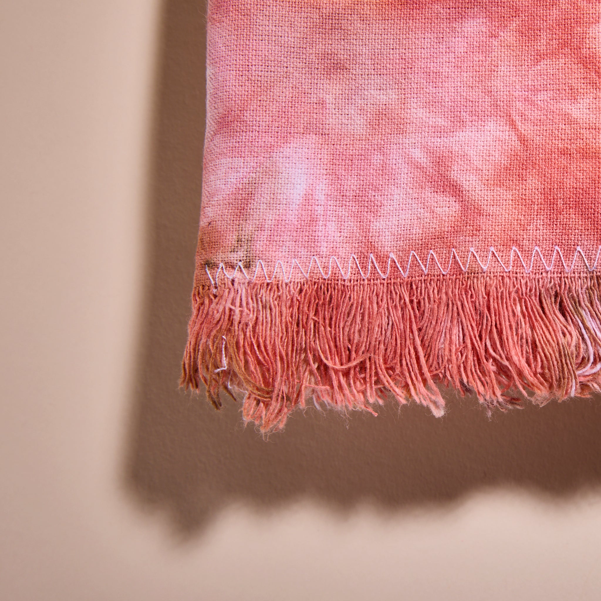 A closeup on a Goldy Way hand-dyed fabric napkin and its fringed edging.