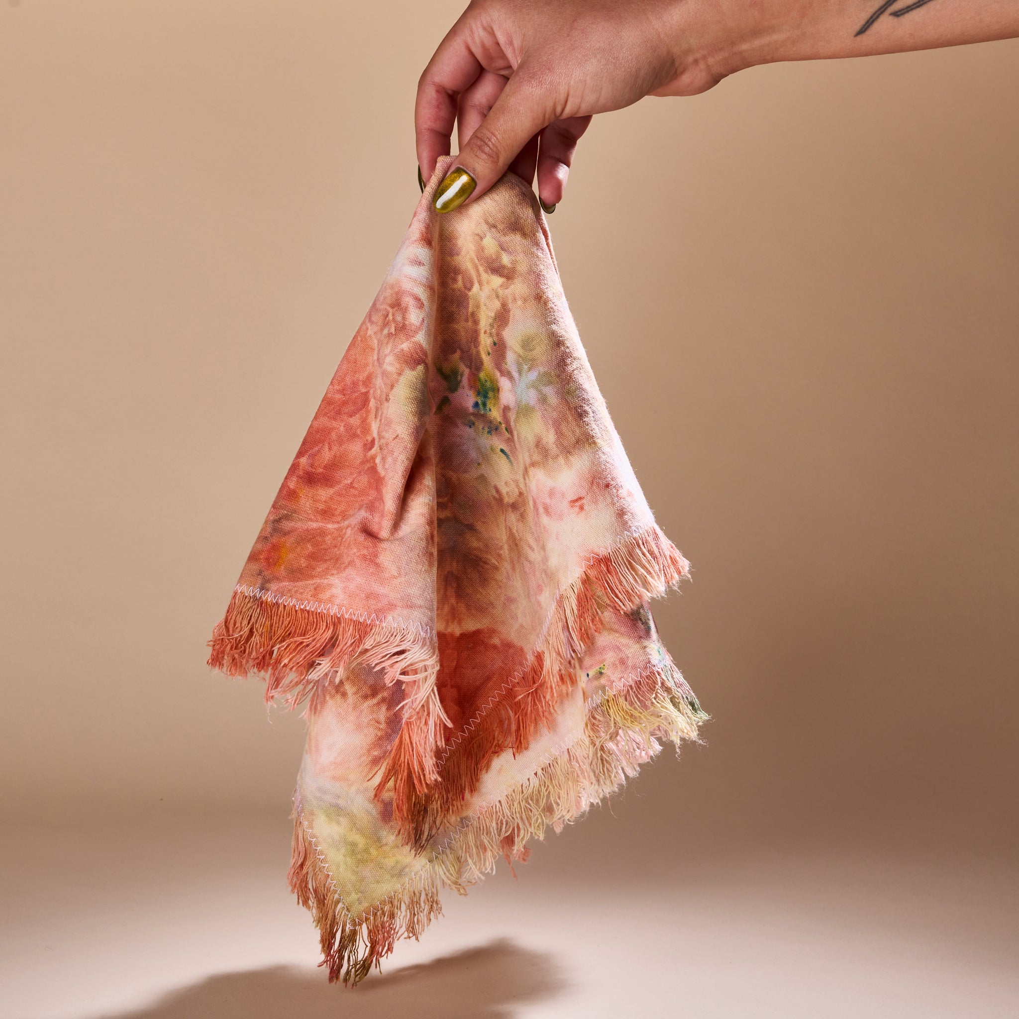 A hand holding a Goldy Way fabric napkin.