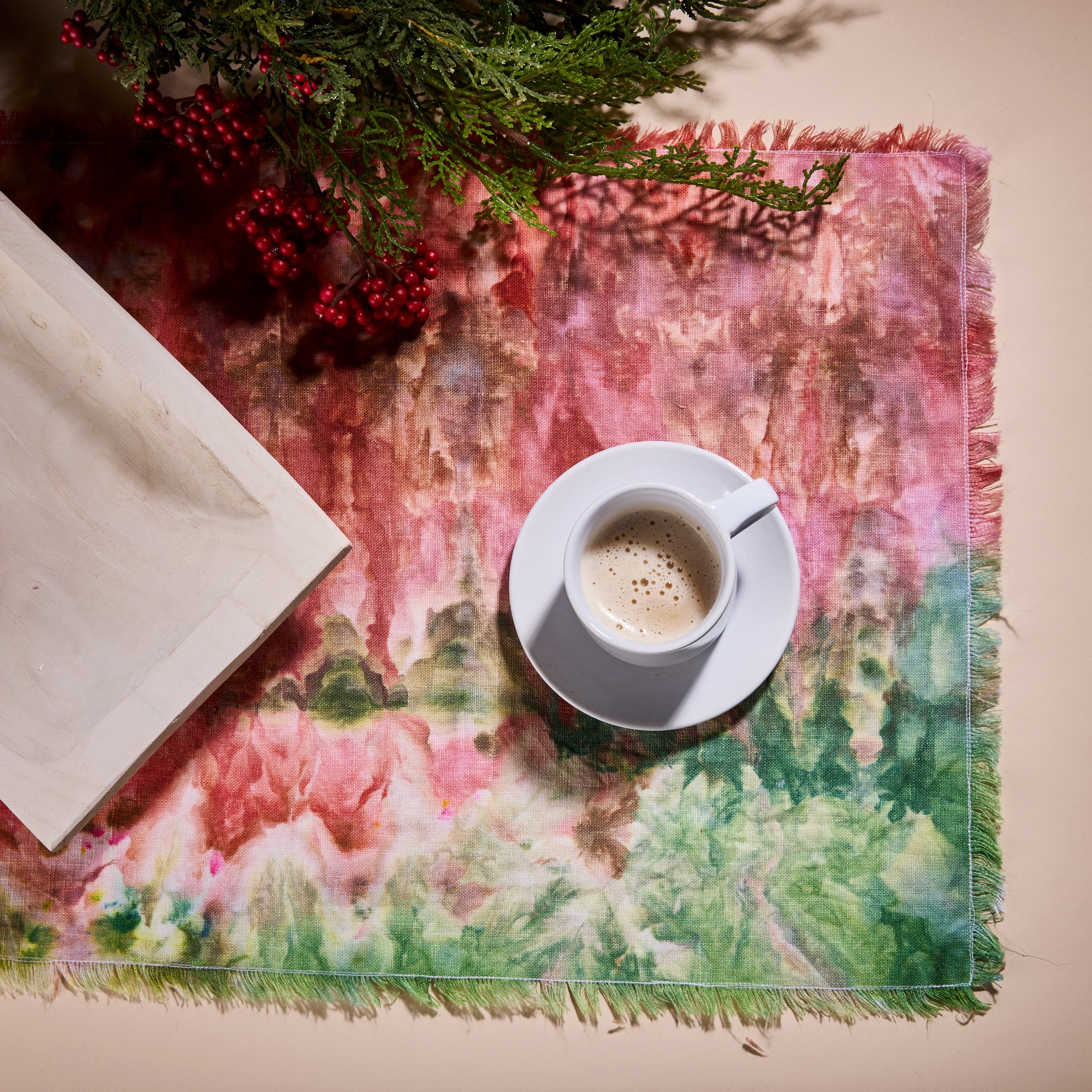 Goldy Way's hand-dyed linen table runner, with a coffee cup, saucer, and notebook placed on top of it.