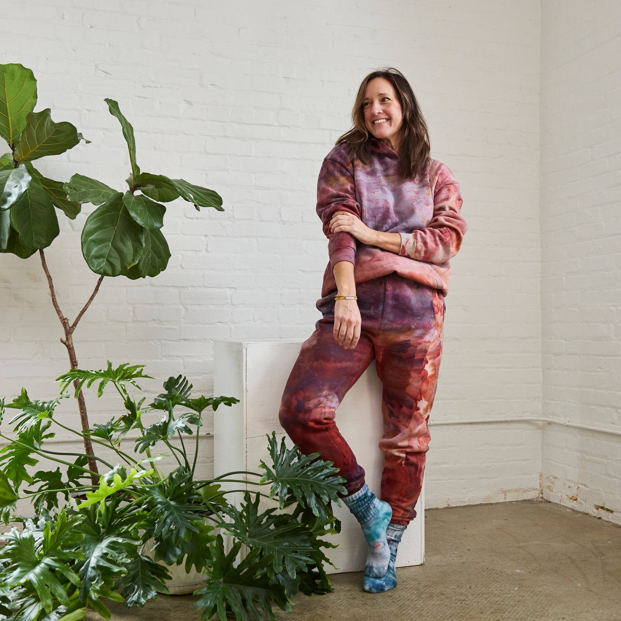 Goldy Way's ice-dyed unisex sweatsuit in the Solstice color. The suit is worn by a model who is also wearing Goldy Way's hand-dyed crew socks in the Lake Effect color.