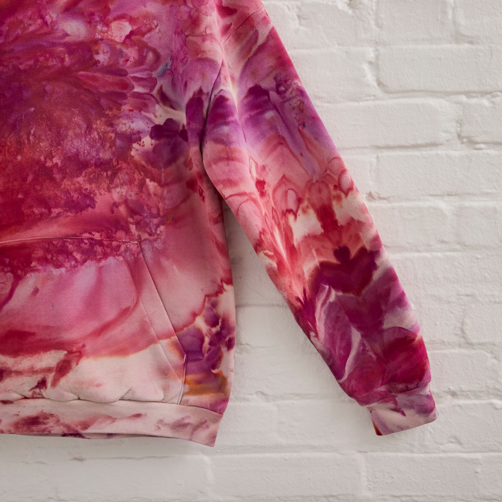 A closeup of Goldy Way's ice-dyed unisex sweatshirt, featuring a sleeve in the Winterberry color.