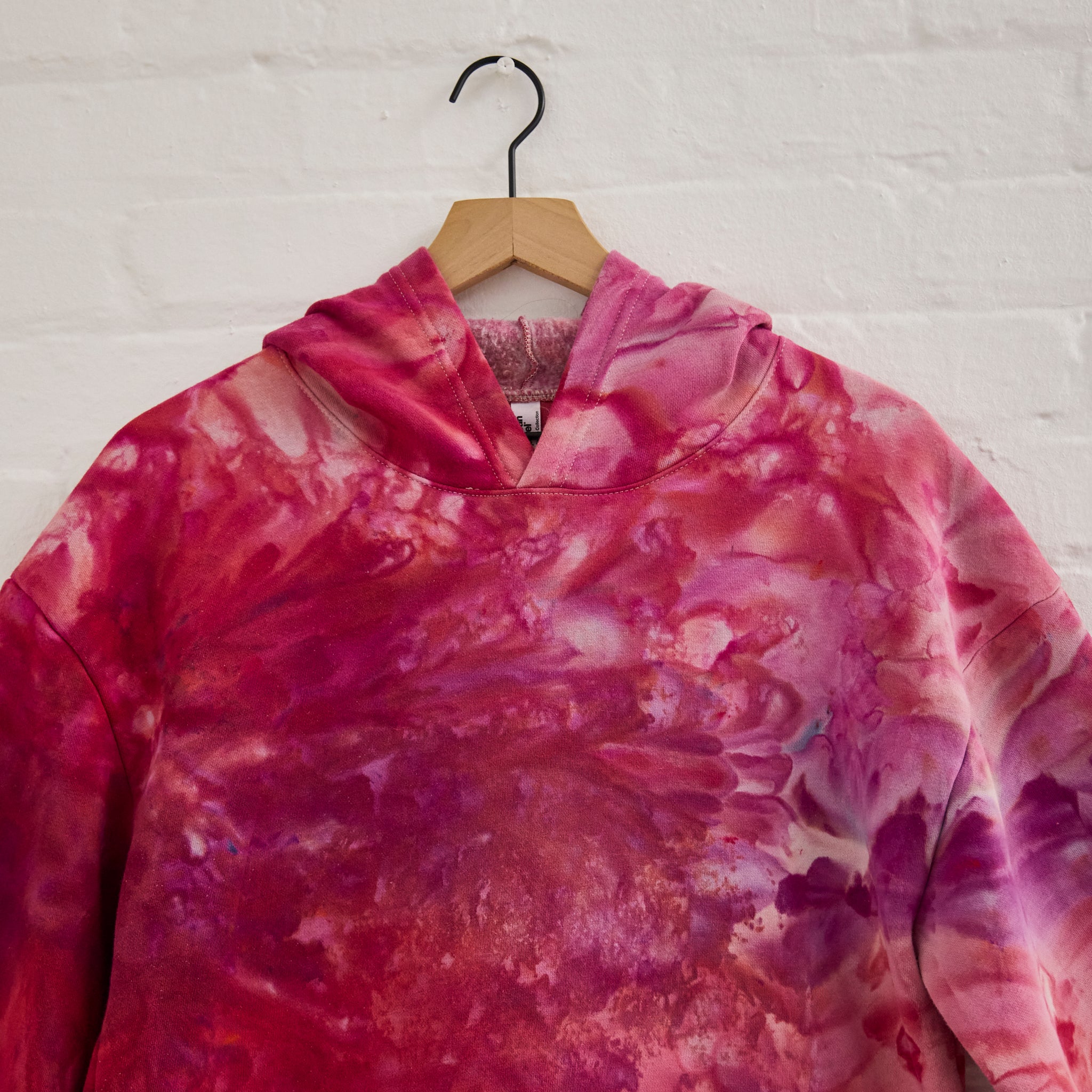 A closeup on the front of Goldy Way's ice-dyed unisex hoodie in the Winterberry color. 