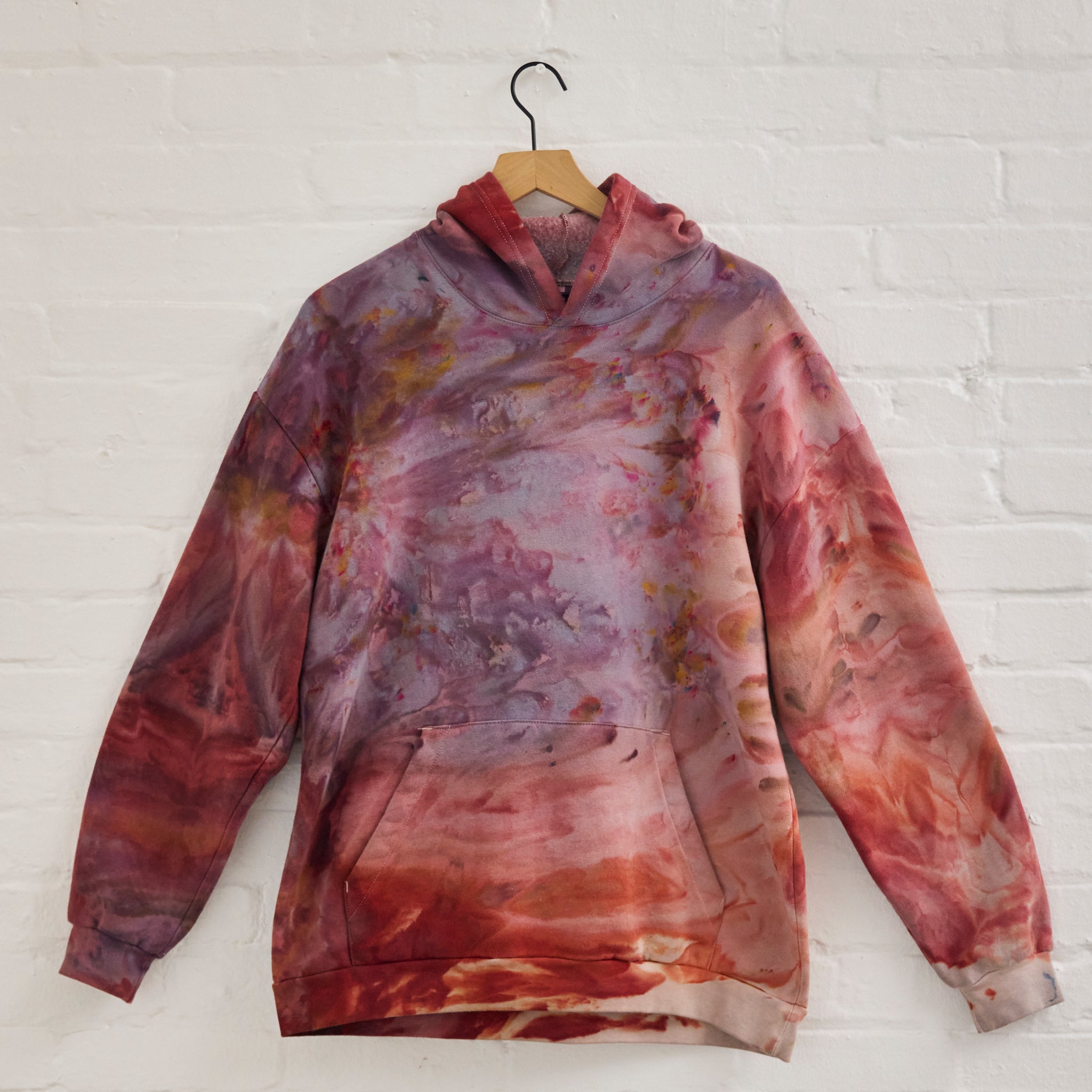 the front of Goldy Way's ice-dyed unisex sweatshirt, with the Solstice color displayed on a hanger.
