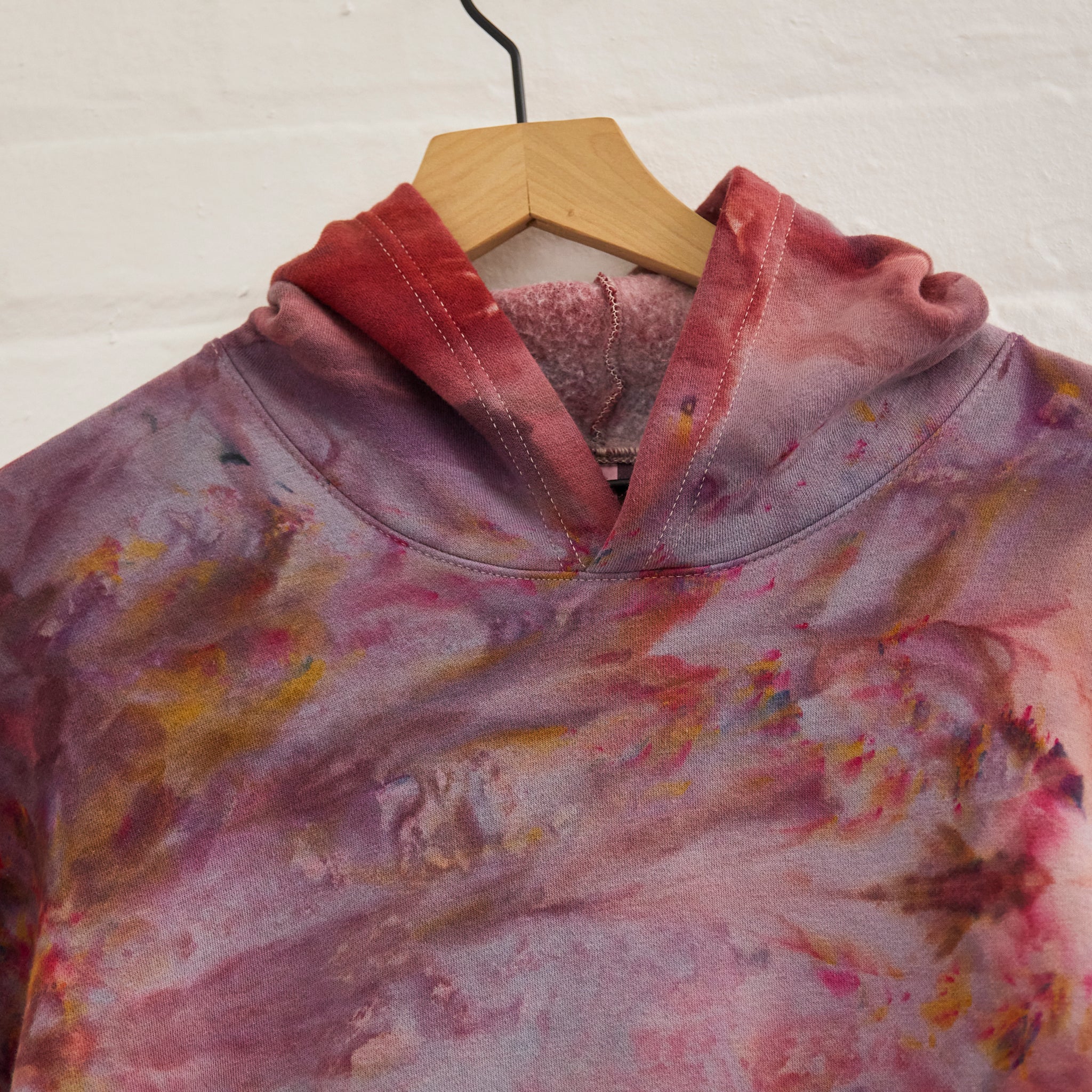 the front of Goldy Way's ice-dyed unisex sweatshirt, with the Solstice color displayed on a hanger.