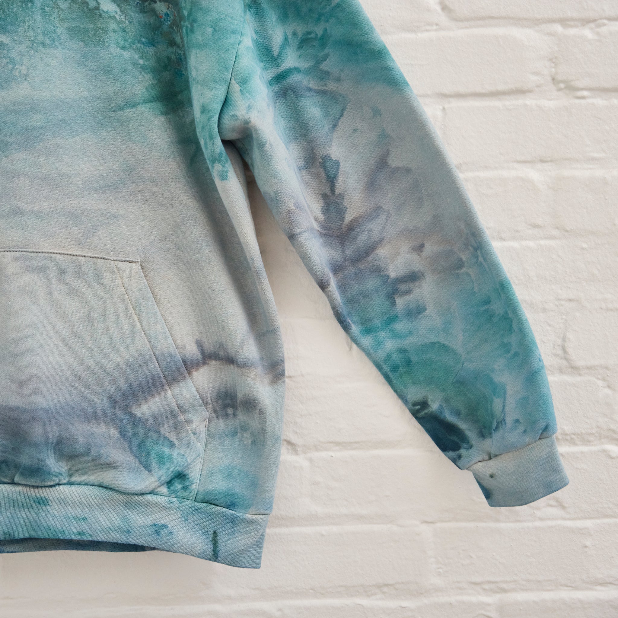 A closeup of Goldy Way's ice-dyed unisex sweatshirt, featuring a sleeve in the Lake Effect color.