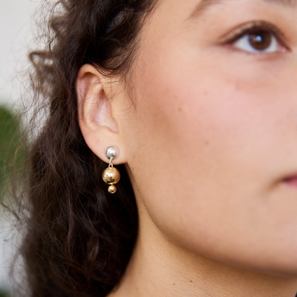 One of Peg's Hardware's Sol earrings, hanging from a model's ear.