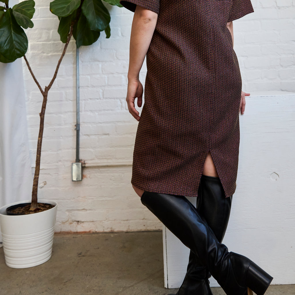 a closeup of the back slit on ARW's deep V block dress, featuring the metallic jacquard style and worn on a model.