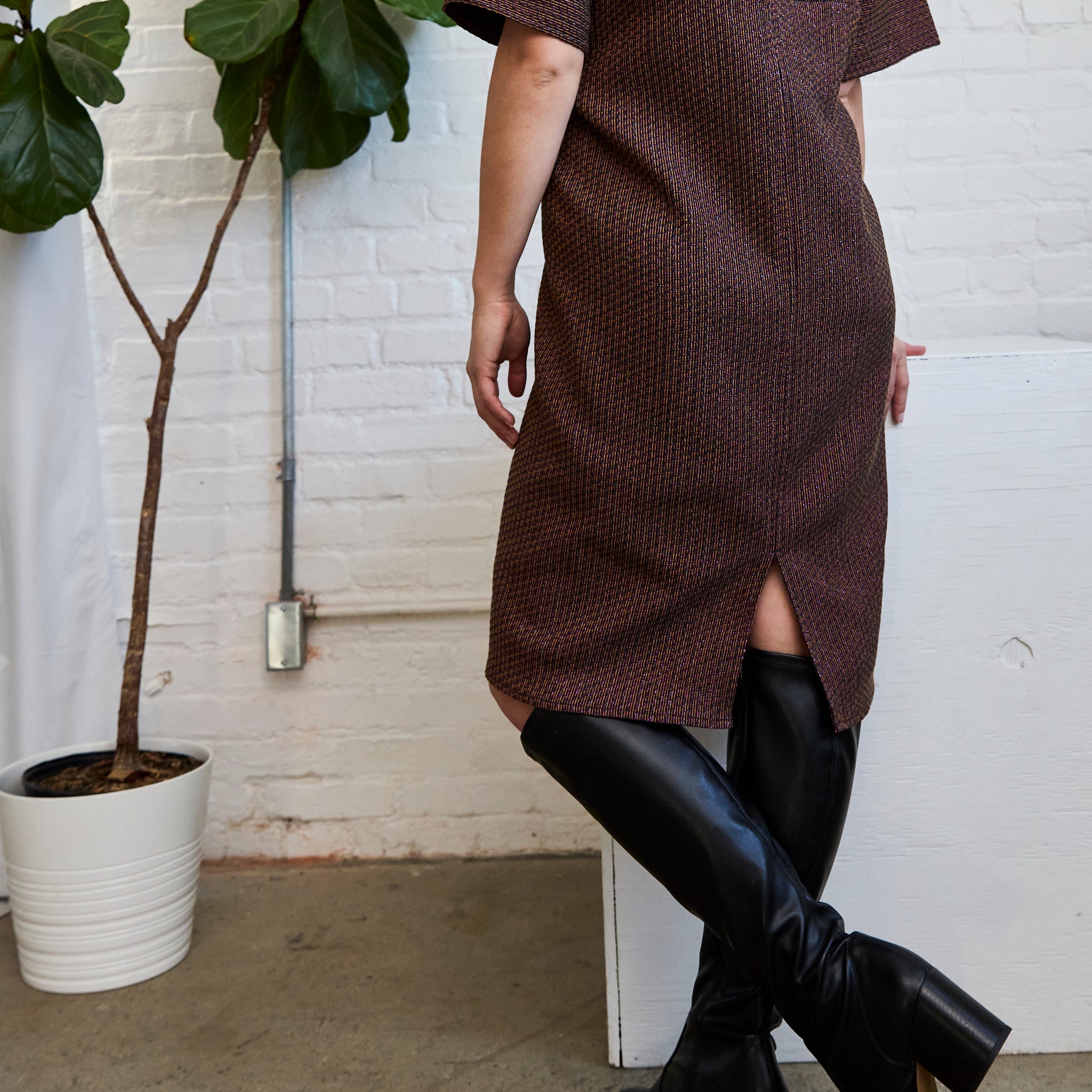 a closeup of the back slit on ARW's deep V block dress, featuring the metallic jacquard style and worn on a model.