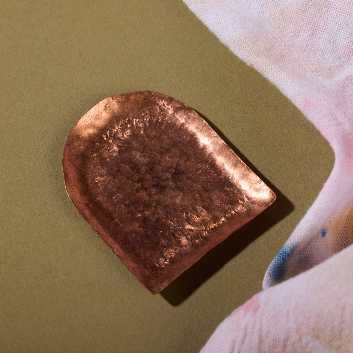 A semicurcular hammered bronze tray sits on a counter.