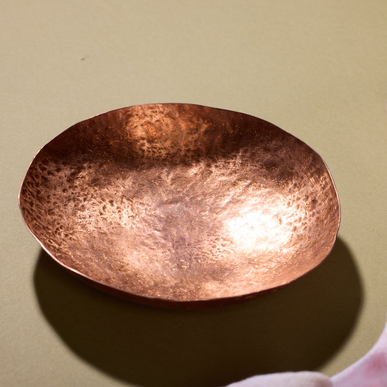 A small bronze hammered circular bowl sits on a counter.