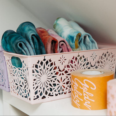 Decorative storage basket with rolled-up socks on a shelf.