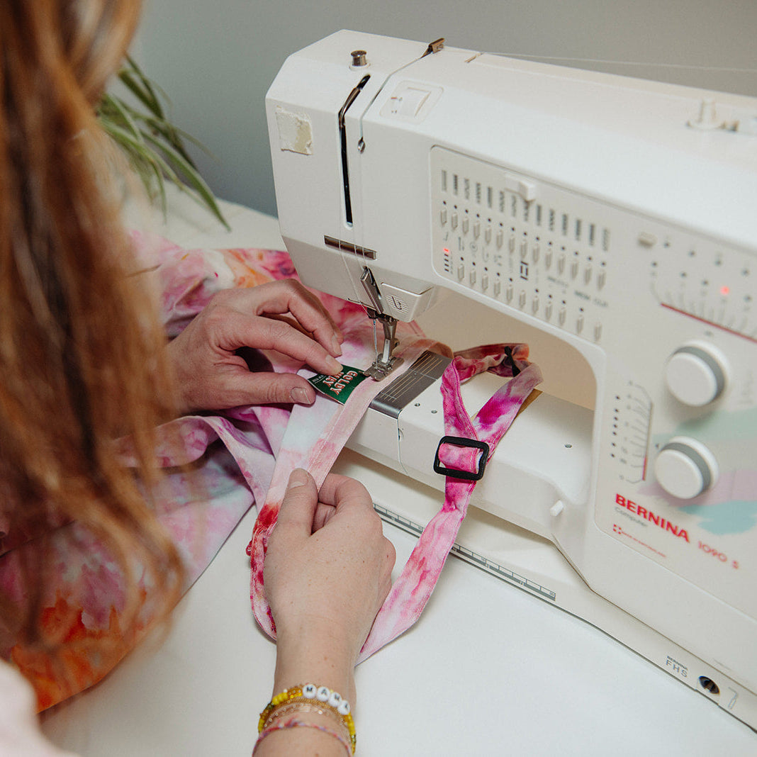Katie Addo sewing Goldy Way label onto apron