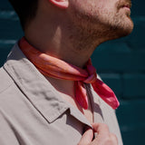 A tied ice-dyed bandana worn around a man's neck.