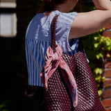 An ice-dyed bandana tied around the handle of a purse.