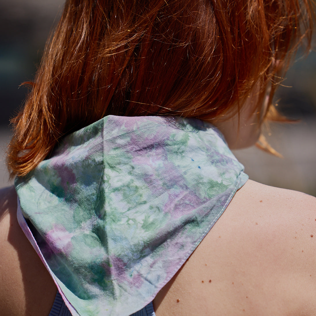 An ice-dyed bandana is tied around a woman's neck.