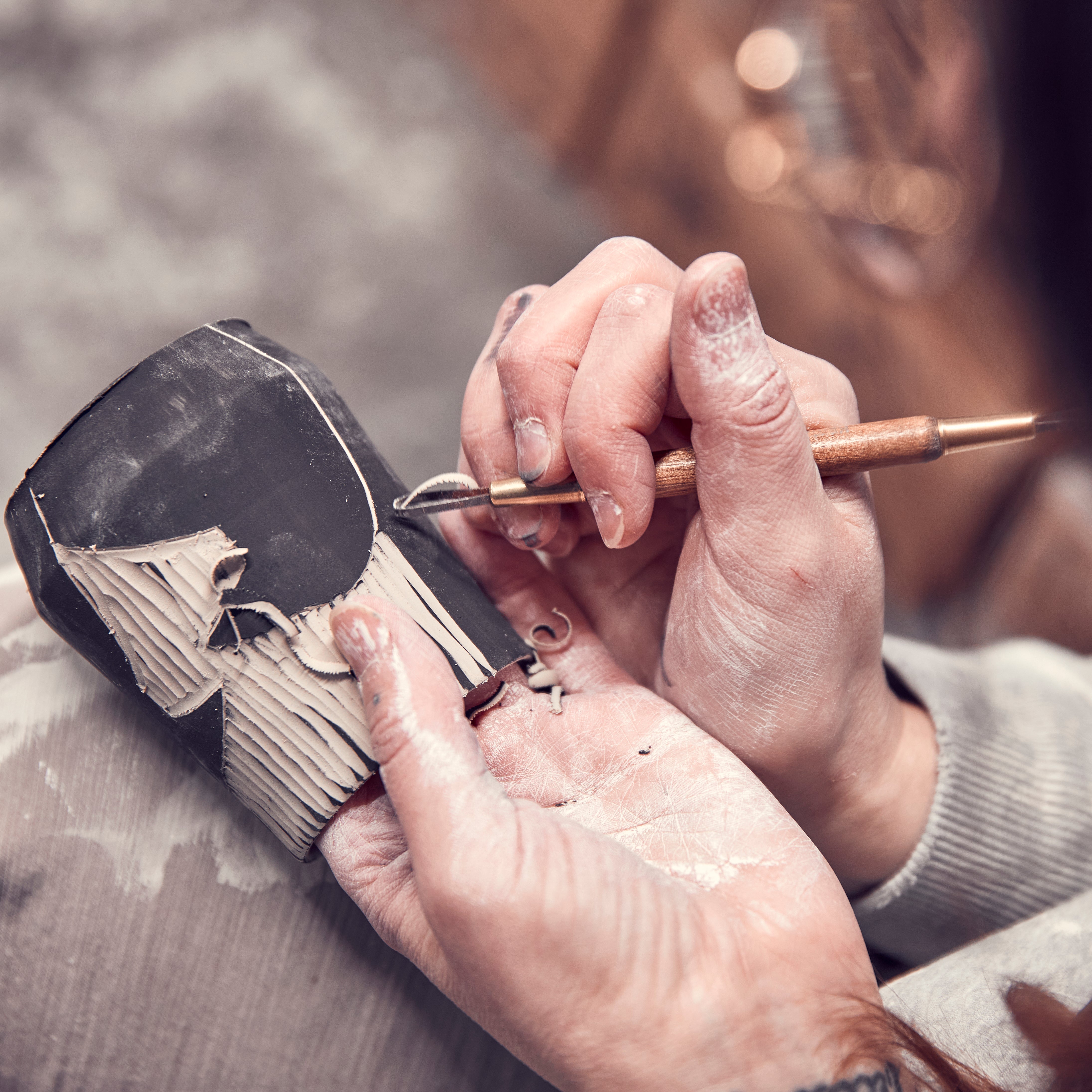 Ceramic artist at work carving a design into a mug