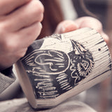 Ceramic artists hands as she carves a raven into a mug