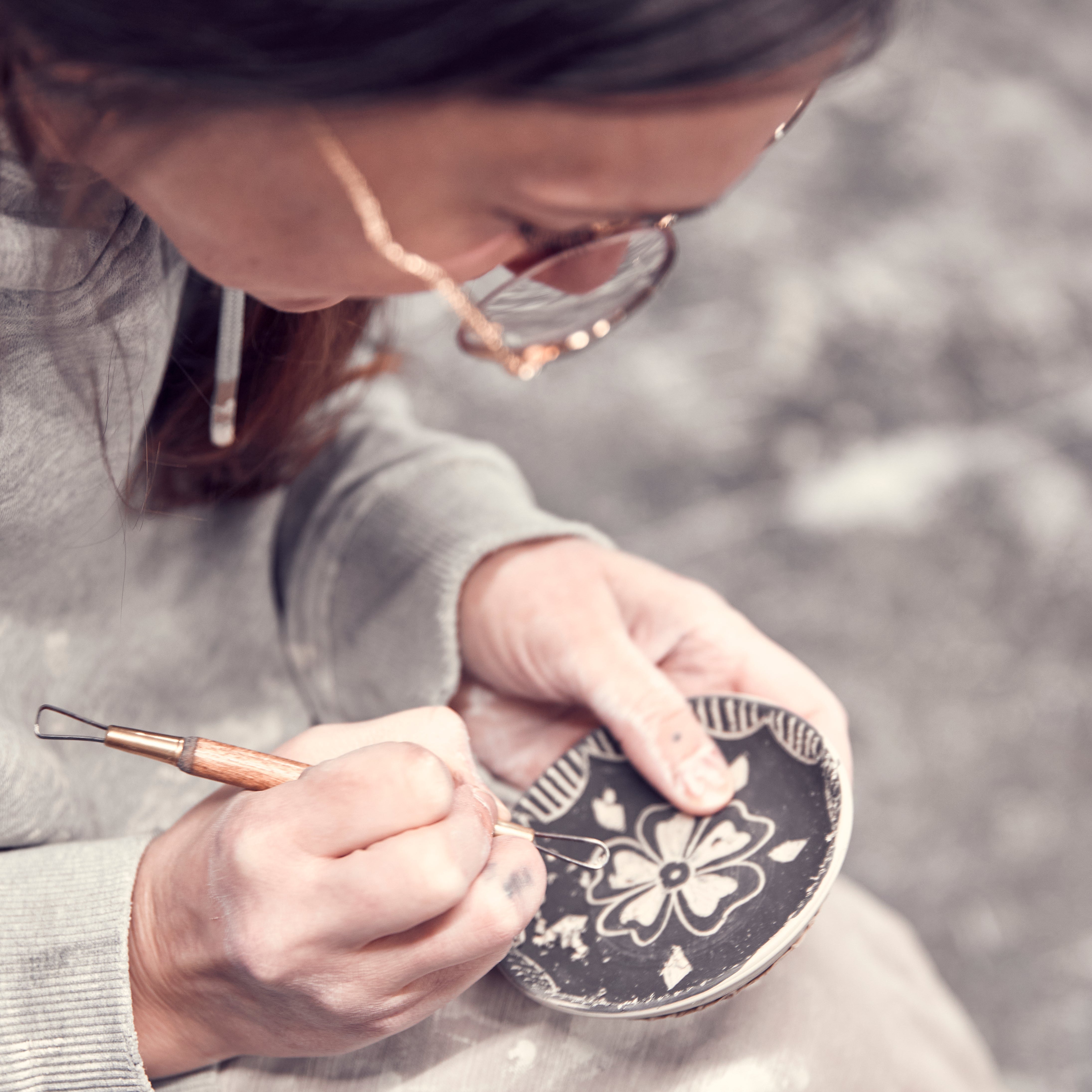 Buffalo NY ceramic artist hand carving flower design into dish
